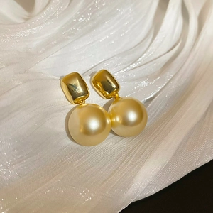 Détail de boucles d'oreilles perles champagne plaquées or 18K sur tissu texturé blanc