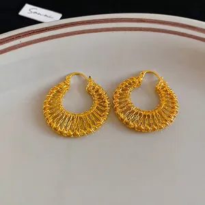 Detailed macro view of 18k gold plated hollow woven hoop earrings with metallic texture
