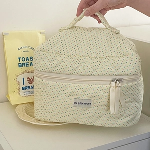Close-up of cream quilted cotton makeup bag with colorful polka dots and sturdy handle