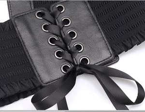 Detail of black corset belt with PU leather panel, metal eyelets and lace-up ribbon bow