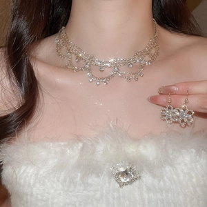Detail of luxury gold flower necklace and crystal earrings set on female model neck