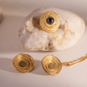 Detailed view of vintage gold coil jewelry set with black onyx on white natural stone
