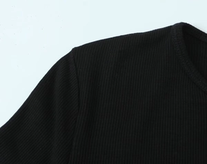 Gros plan sur le tissu en maille côtelée noire et les coutures d'épaule d'un haut long