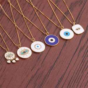 Gold-plated copper Fatima Evil Eye necklaces with enamel and zircons on wood background