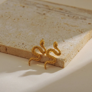 Macro detail of gold snake stud earrings with realistic scale texture on marble