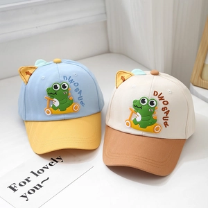 Detail of dinosaur cartoon baseball caps for kids in light blue and beige colors