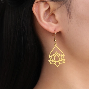 Close-up of golden hollow lotus pendant earrings worn on model for an elegant look