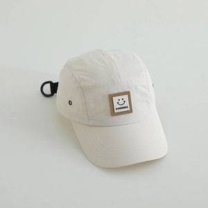 Detail view of beige quick-dry baseball cap featuring a smile and KINDNESS woven patch