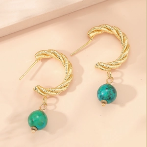Dettaglio macro di orecchini a cerchio ritorti in oro 14k con perle verde marmo