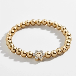 Detailed close-up of golden beaded bracelet with a sparkling crystal flower smiley face charm