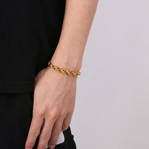 Detail of a golden twisted chain bracelet on a wrist with rich metallic texture