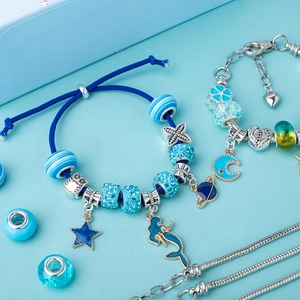 Macro detail of DIY jewelry set featuring blue galaxy charms and silver snake chains