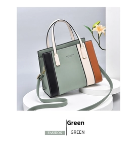 Detailed view of color-block tote bag with top handle and shoulder strap on white stand