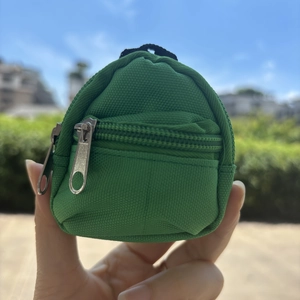 Close-up of a mini green canvas backpack coin purse with double zippers and metal hook