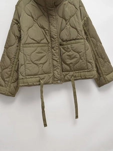 Detail of olive green quilted jacket featuring diamond stitching and large utility pocket