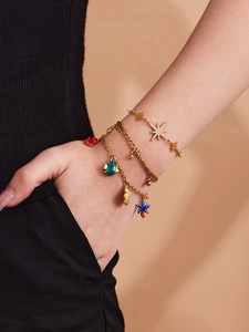 Detailansicht goldener Schichtarmbänder mit Sternmotiven und bunten Meeresanhängern