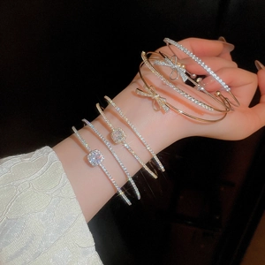 Close-up of stacked bow tie bangles with glittering zircon stones in gold and silver