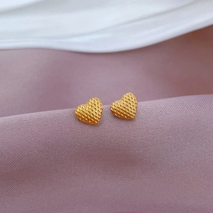 Minimalist gold heart stud earrings with checkered texture on purple silk background