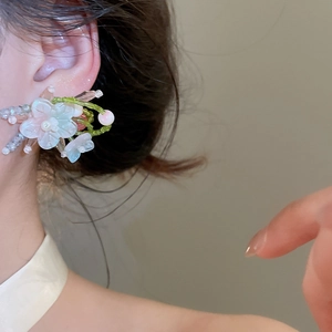 Detalle de primer plano de pendientes florales con cuentas de cristal verdes y rosas