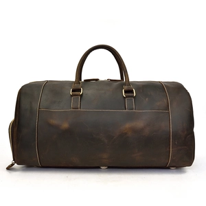 Detail of vintage dark brown leather duffel bag with dual handles and white stitching