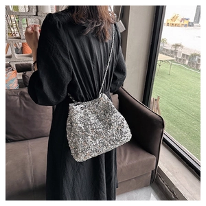 Close-up of sparkling silver sequin bucket bag with elegant metallic chain strap detail