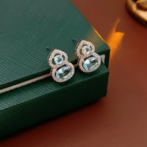 Close-up of silver gourd earrings with blue gemstones and diamonds on jewelry box