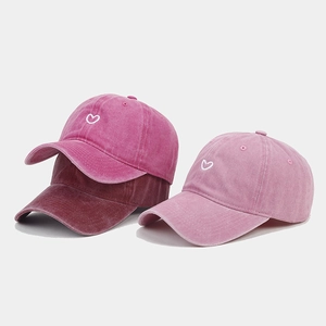 Detailed embroidery of heart on washed cotton baseball caps in three shades of red