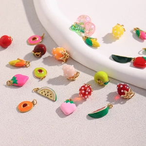 Detailed close-up of fruit-shaped gold plated enamel pendants for DIY jewelry making
