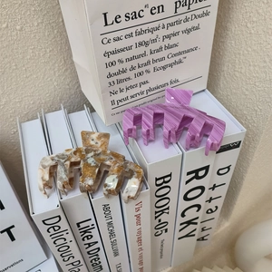 Détail de pinces à cheveux à rayures violettes et marbrées sur des livres et sacs