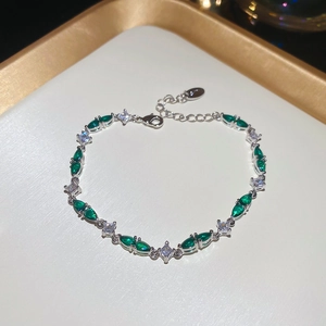 Detail view of emerald green stones and white cubic zirconia on a silver chain bracelet