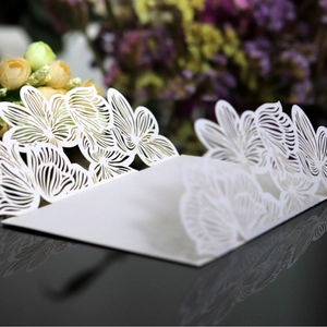 White laser cut floral wedding invitation card with elegant hollow rose pattern on black surface