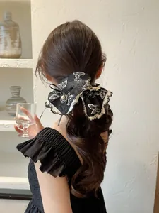 Detail of a large black rose pattern bow hairband with lace trim and a pearl pendant