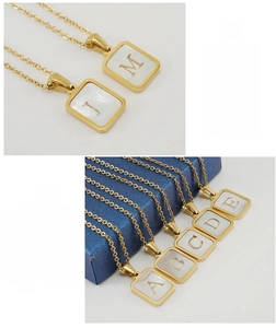 Vue macro détaillée des pendentifs lettres carrés en nacre et acier inoxydable doré 18K