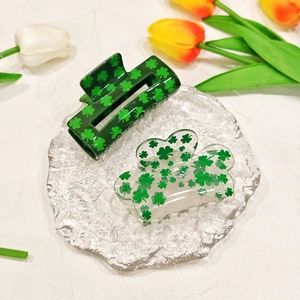 Elegant green acrylic four-leaf clover hair claws on a glass plate with tulips