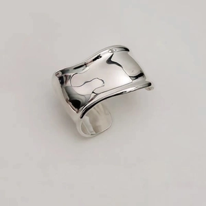 Vue macro d'une large bague ondulée ajustable en argent avec une finition métallique polie