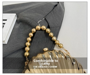 Detail of golden shell evening bag featuring textured ridges and beaded top handle