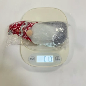 Poupée gnome de Noël faite main pesée sur une balance numérique affichant 61,8 g