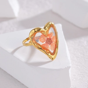 Detailed view of a gold-plated ring featuring an orange dried flower in clear resin