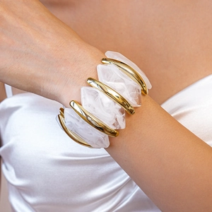 Détail d'un bracelet extensible large avec segments en métal doré et pierres de résine laiteuse