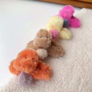 Detailed plush poodle-shaped claw clips in orange, brown, and pink with soft faux fur texture