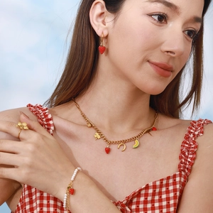 Model wearing strawberry jewelry set with red enamel earrings and pearl bracelet
