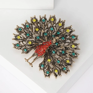 Macro shot of peacock brooch with colorful rhinestones on a white geometric display