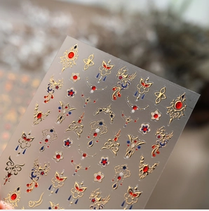 Macro detail of Chinese retro gold butterfly and phoenix nail art decals with blue accents