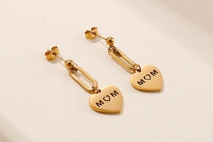 Detailed view of heart-shaped gold stud earrings with MOM engraving in titanium steel