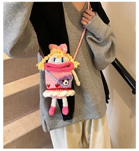Girl wearing a handmade pink crochet crossbody bag with cartoon doll and bear decor