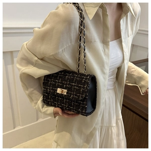 Close-up of black tweed shoulder bag with gold chain strap and metal square twist lock