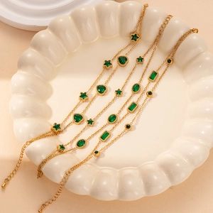 Detailed macro view of four gold-plated bracelets featuring green star and heart stones