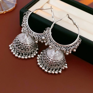 Macro shot showing intricate silver metal details of Jhumka style earrings on dark wood