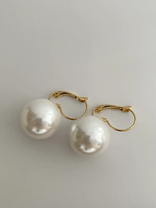 Detail of 14K gold plated hoop earrings featuring large round white resin pearls
