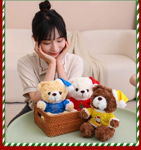 Close-up of three festive teddy bears in a woven basket wearing colorful Christmas outfits